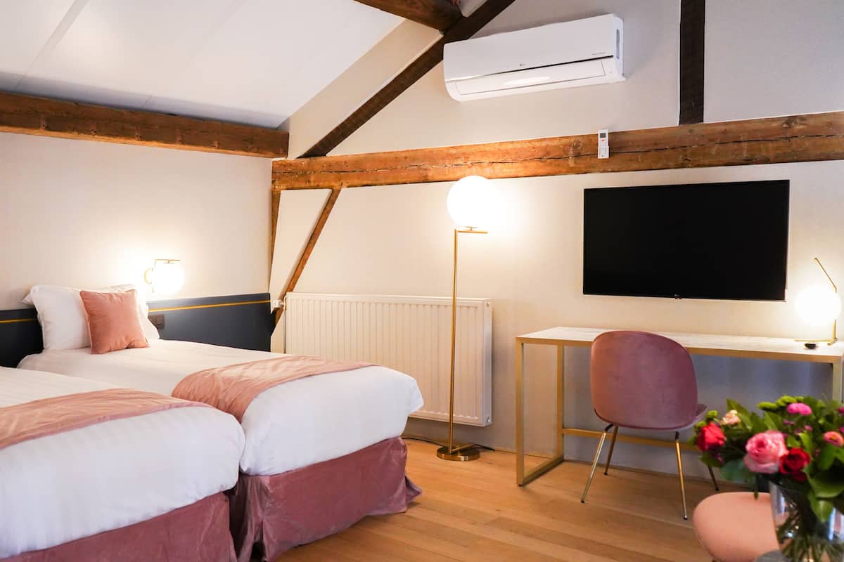 Een slaapkamer met twee bedden, een bureau, een stoel en een televisie.