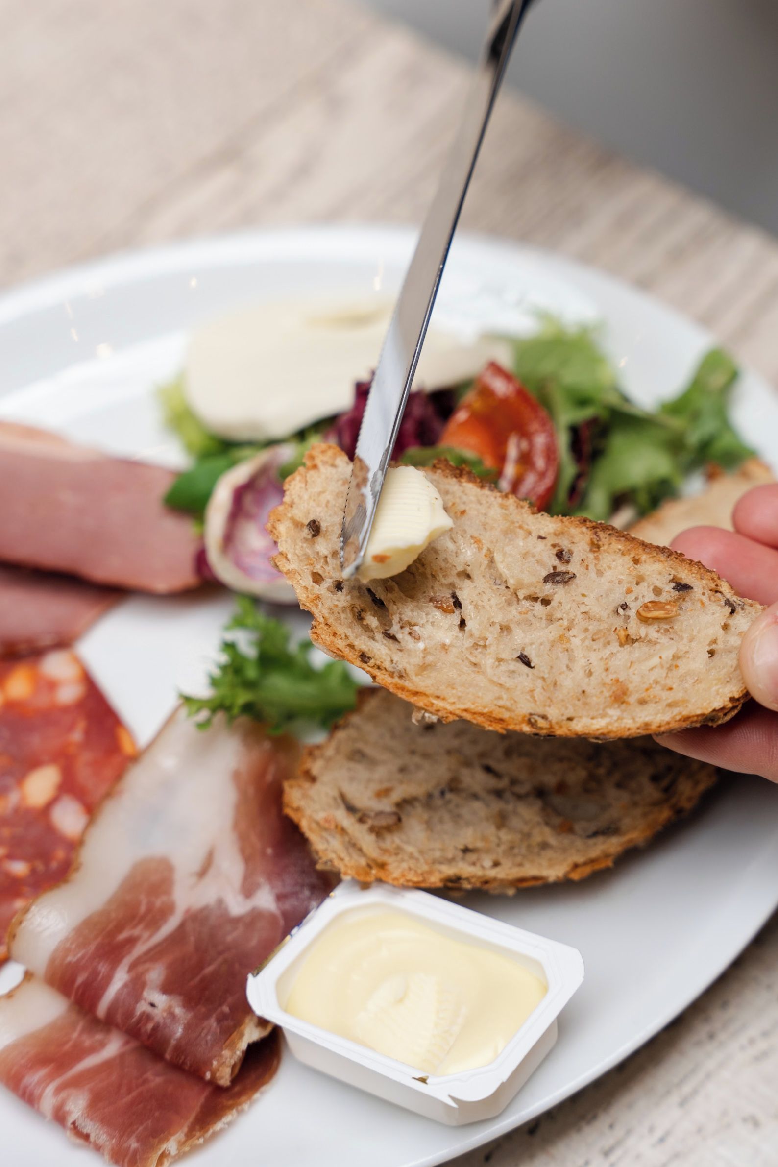 Un plato con diferentes alimentos, incluyendo pan, queso y embutidos.
