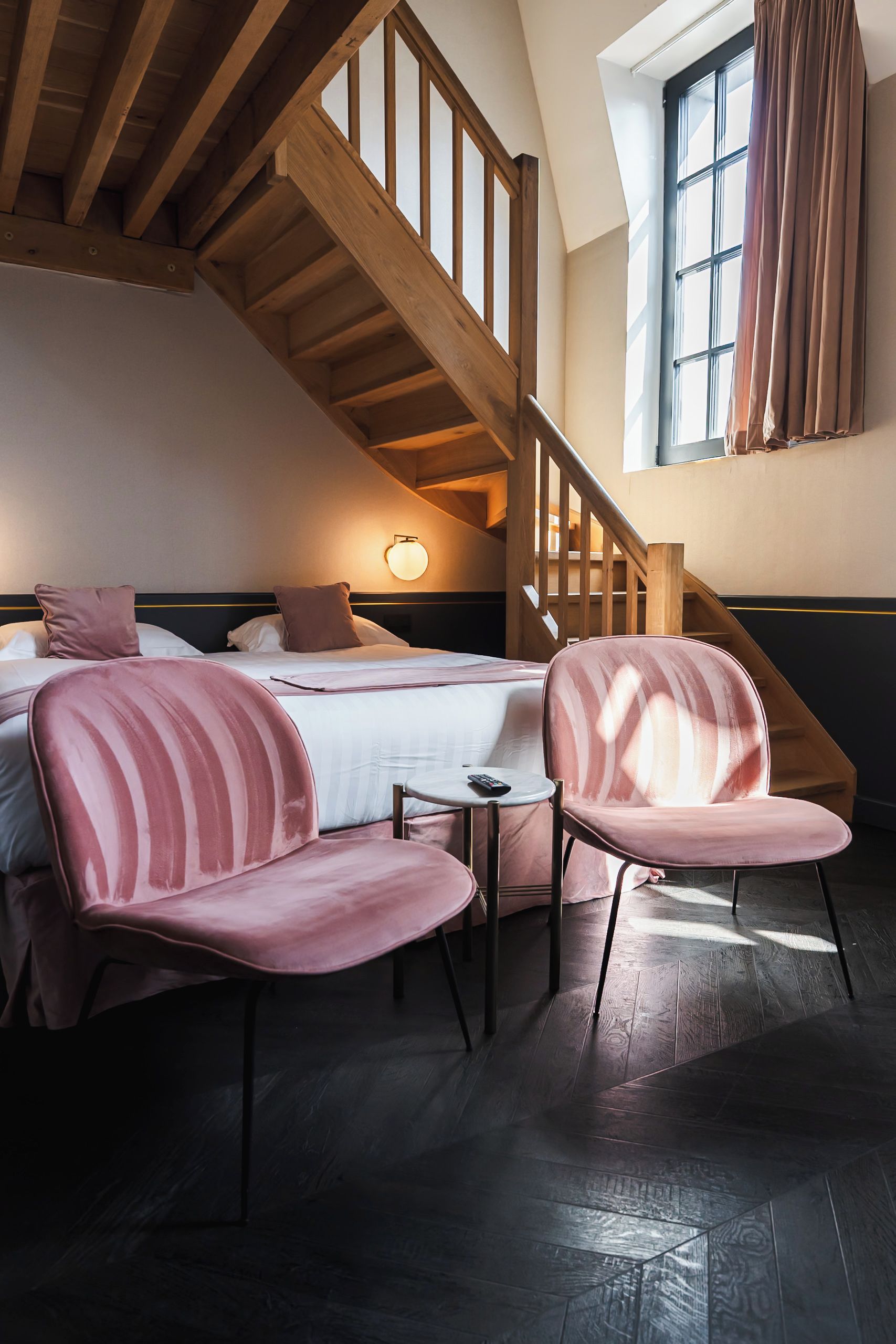 Un dormitorio con cama, dos sillas, una mesita y una escalera.