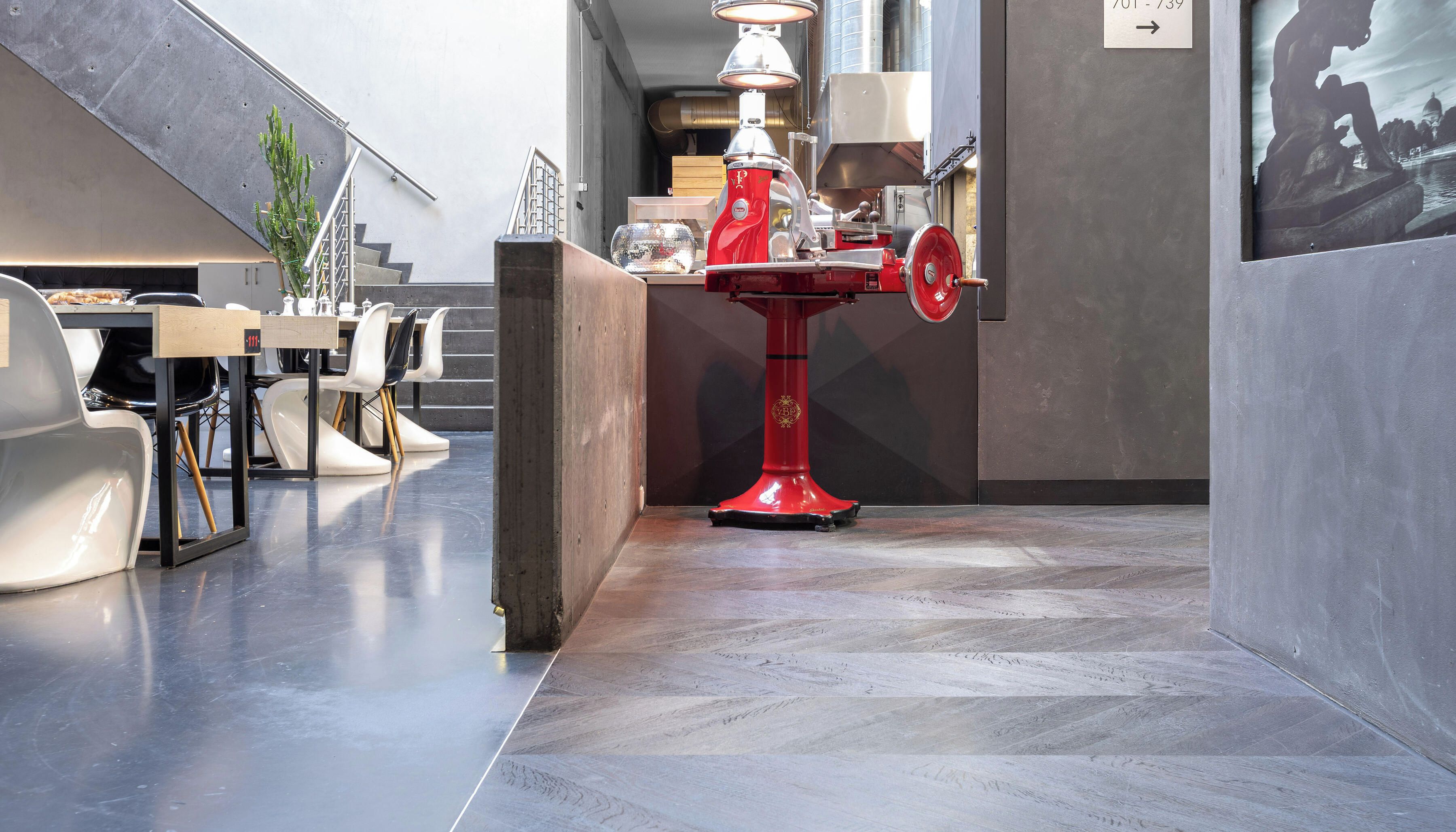 Un intérieur moderne avec une table sur pied de couleur rouge, un escalier et un coin repas avec des chaises blanches.