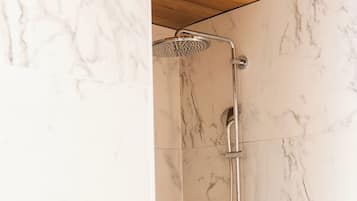 Een douche met een handdouche en een kraan op de muur in een badkamer met marmeren wanden.