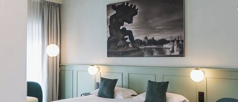 A hotel room with a large bed, two bedside tables, a chair, and a painting on the wall.