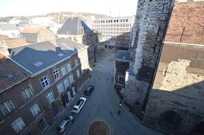 Une cour avec une fontaine, entourée de bâtiments historiques aux façades en briques et d’une grande tour de pierre.