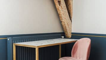 Una habitación con un escritorio de madera, una silla rosa y vigas de madera a la vista.