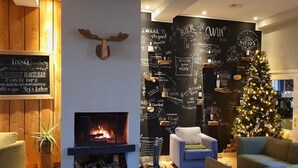 Een gezellige zithoek met een open haard, een kerstboom en een muur versierd met uitspraken over bier.