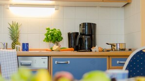 Een keuken met een koffiezetapparaat, een ananas en een plant op het aanrecht.