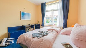 Hotelkamer met een bed, een bureau, een stoel, een raam met gordijnen en een schilderij aan de muur.