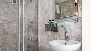 A bathroom with a glass shower enclosure, a white sink, and a mirror above the sink. - Hotel Rose Bouquets (Istanbul)