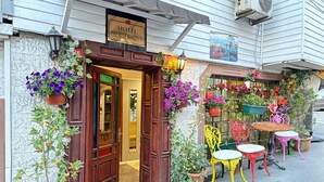 A hotel entrance with a wooden door, a red carpet, and colorful outdoor furniture. - Hotel Rose Bouquets (Istanbul)