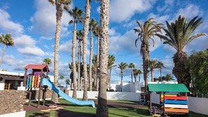 A playground with a slide, swings, and a climbing structure. - Ona Las Brisas (Yaiza)