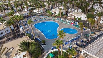 Una piscina al aire libre, sillones reclinables de piscina