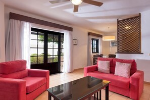 A living room with two red sofas, a glass coffee table, and a ceiling fan. - Ona Las Casitas (Yaiza)