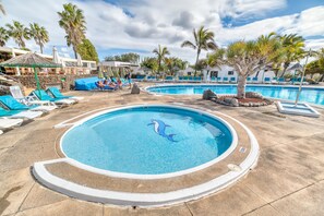 A pool area with lounge chairs and palm trees. - Ona Las Casitas (Yaiza)