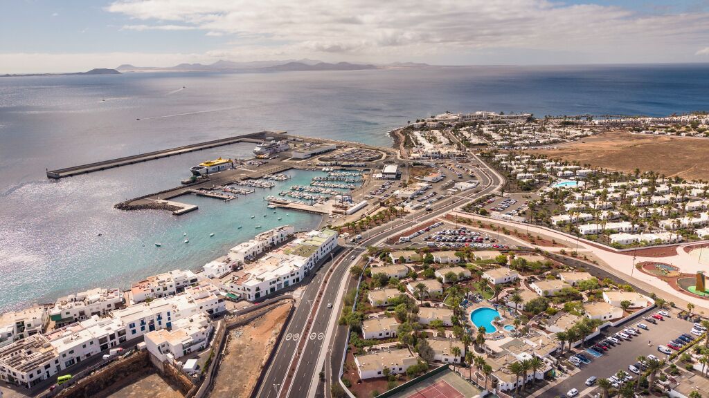 An aerial view of a coastal town with a marina, residential buildings, and a road network.