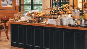 Un comptoir de buffet proposant divers plats, une machine à café et un espace détente avec des chaises.