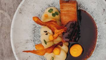A plate of food with various items including a piece of meat, potatoes, and garnishes.