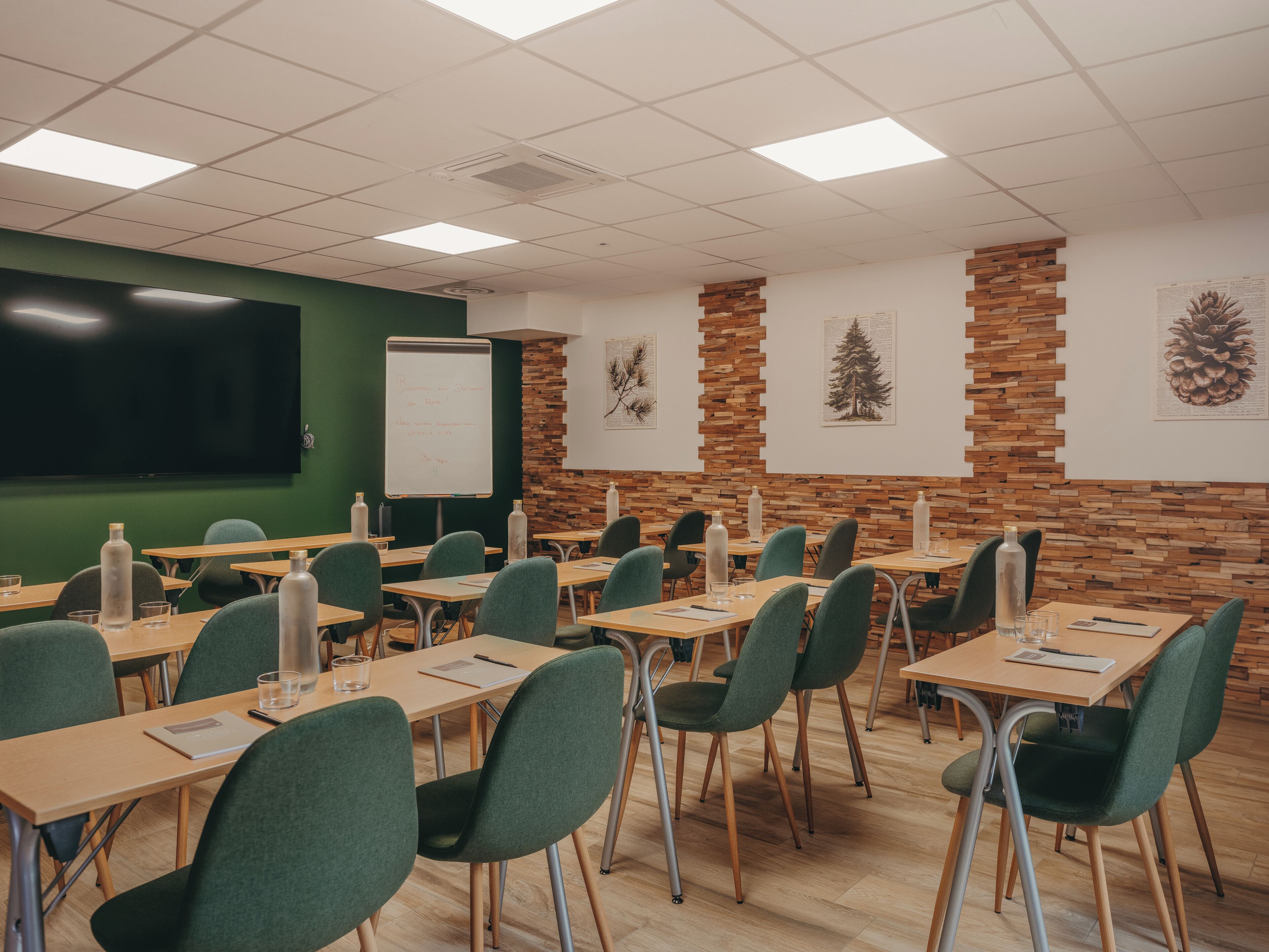 A classroom with desks, chairs, a whiteboard, and educational posters on the walls.