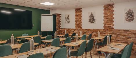 A classroom with desks, chairs, a whiteboard, and educational posters on the walls.