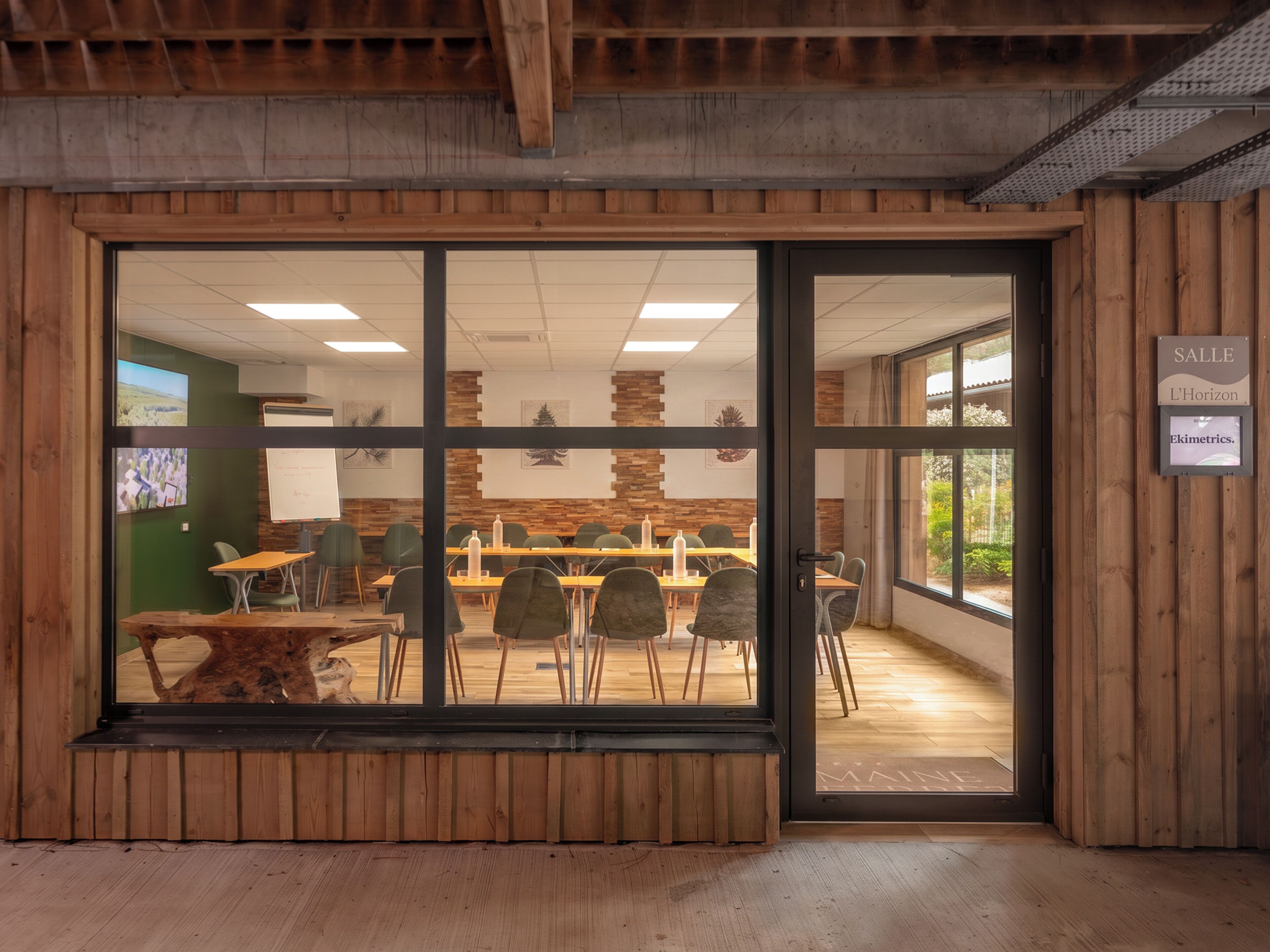 A conference room with a large table, chairs, and a wooden wall.