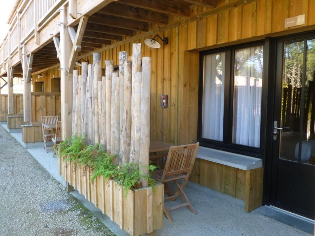 Un bâtiment en bois doté d’un porche abrité, d’une table et de chaises, et d’une fenêtre offrant une vue agréable.