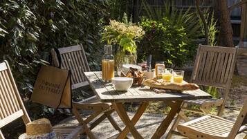 A wooden table with a bottle, bowls, a basket, and a baguette.