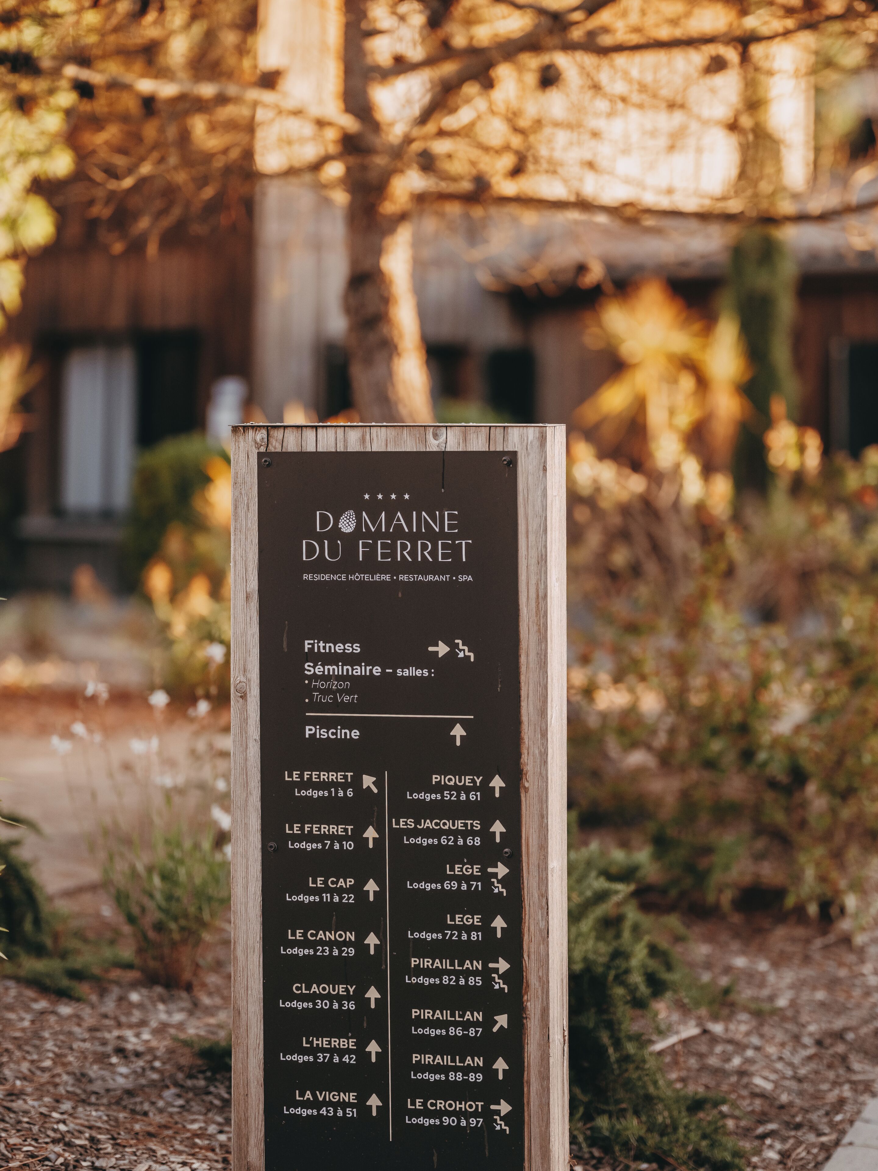 Panneau de signalisation indiquant la direction du Domaine du Ferret, avec une liste des hébergements et des équipements disponibles.