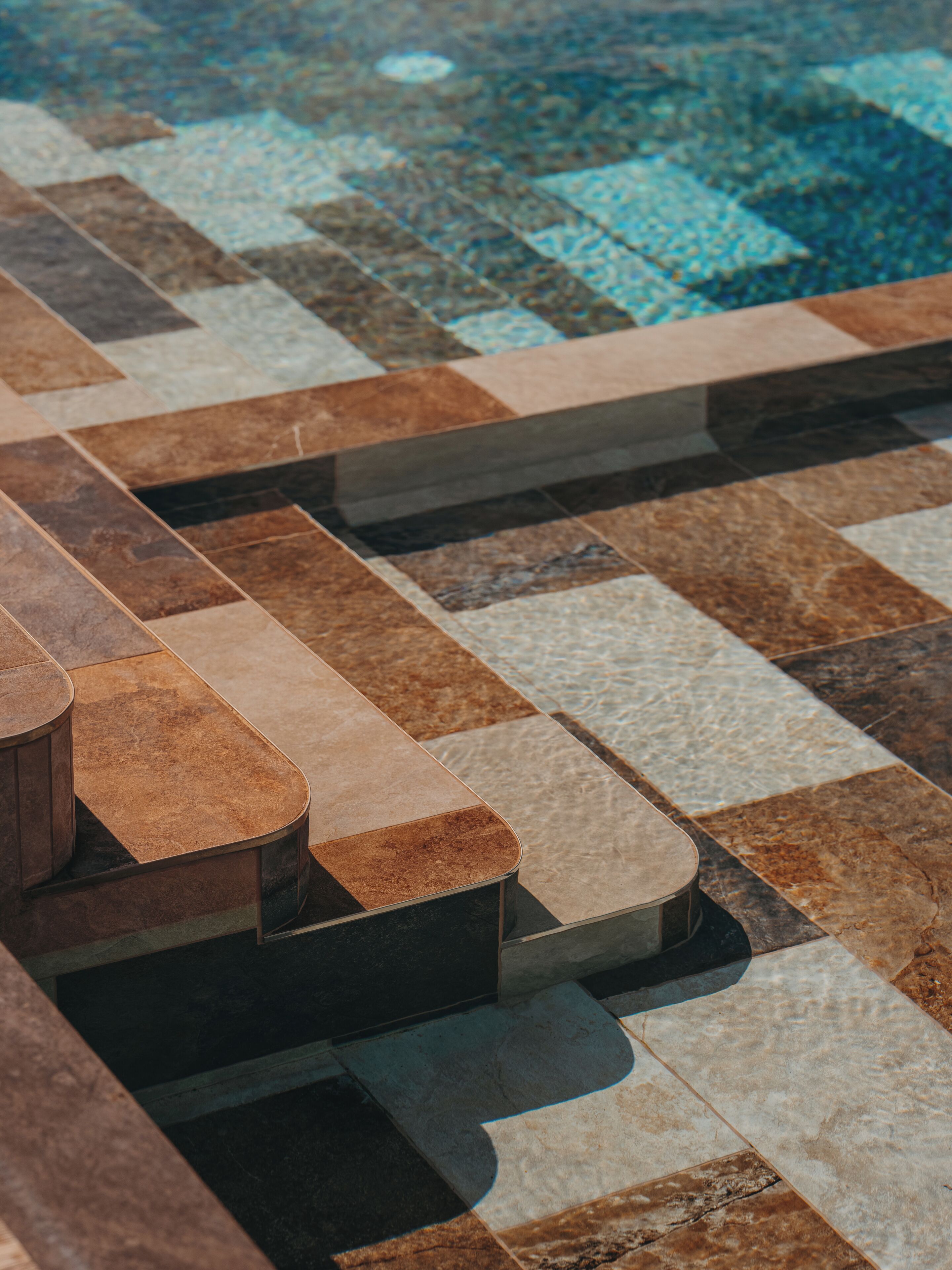 A poolside area with a tiled floor and a wooden bench.