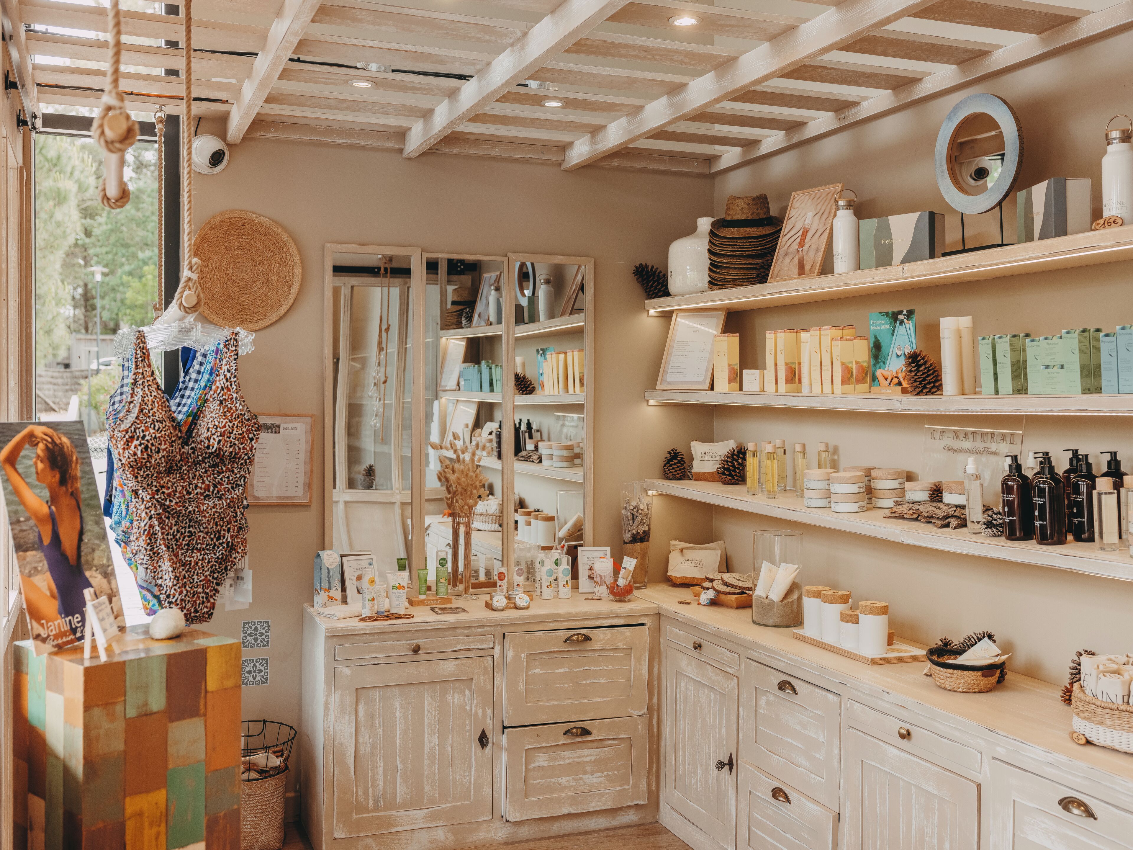 A boutique with wooden shelves displaying various products, a mannequin with a patterned dress, and a rustic interior design.