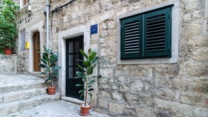 A stone building with a door and window, potted plants, and a sign. - Apartments Raic (Dubrovnik)