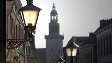 Vista urbana con una torre destacada al fondo y farolas en primer plano.