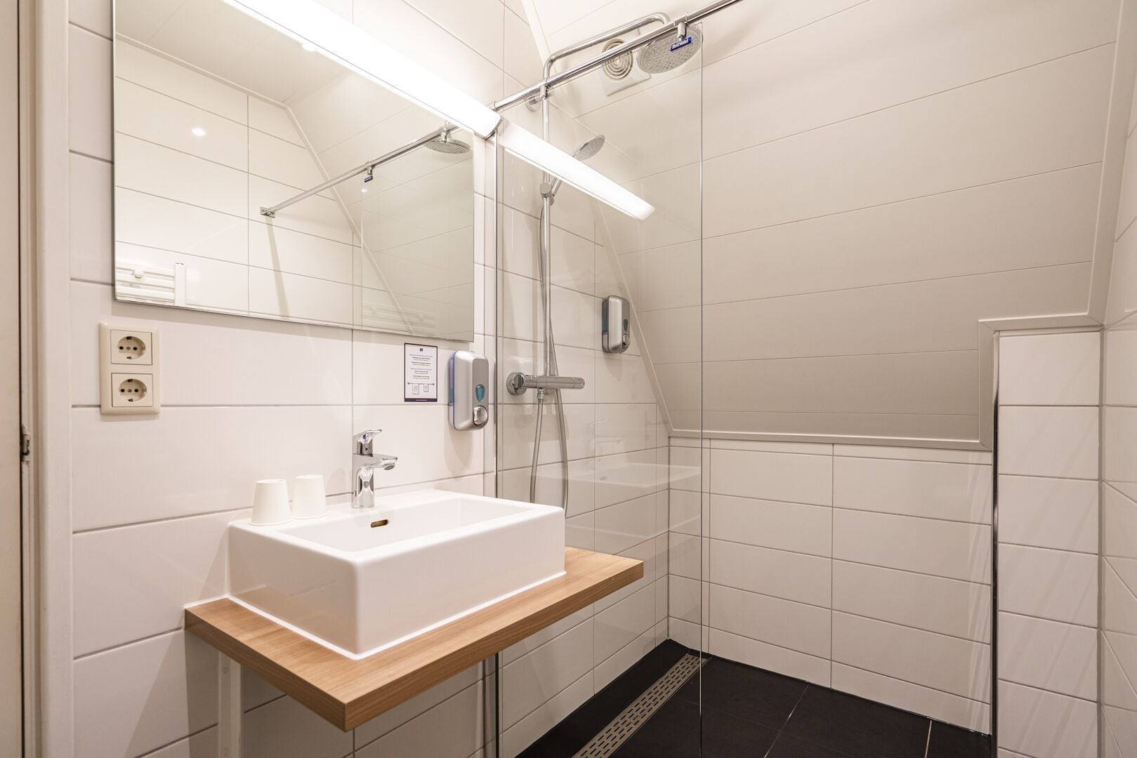 Une salle de bain moderne avec un lavabo blanc, un miroir et une douche.