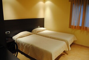A room with two single beds, a desk, and a chair.
