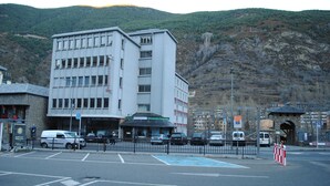 A multi-story building with a restaurant on the ground floor, a parking area, and a mountainous backdrop. - La Mola (Encamp)
