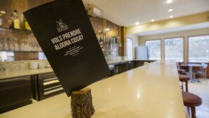 A menu stand with a black menu titled "VOLS PRENDRE ALGUNA COSA?" in a restaurant setting. - La Mola (Encamp)