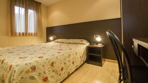 A hotel room with a bed, bedside table, lamp, and a chair. - La Mola (Encamp)