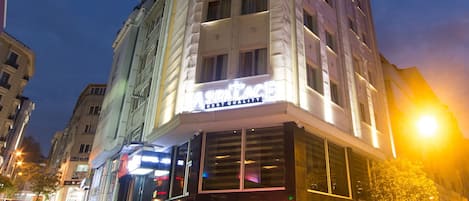A hotel with a modern facade, large windows, and a prominent illuminated sign.