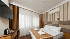Camera d'albergo con un letto, una scrivania con bollitore, una TV e un condizionatore d'aria.