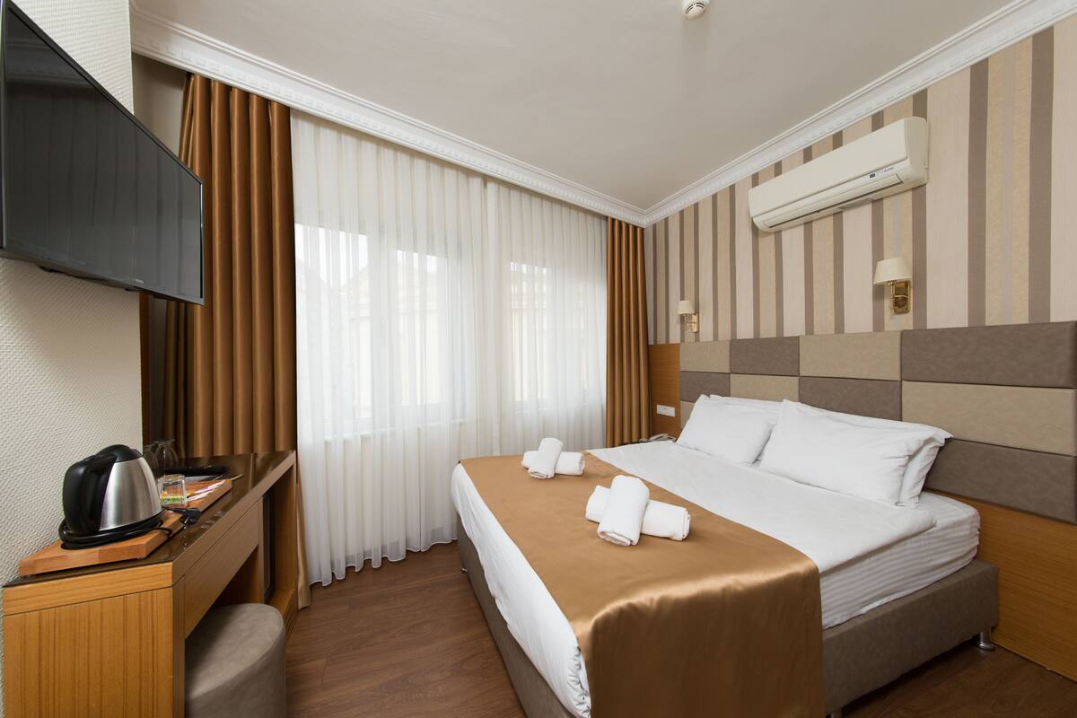 Une chambre d’hôtel équipée d’un lit, d’un bureau avec une bouilloire, d’une télévision et d’un appareil de climatisation.