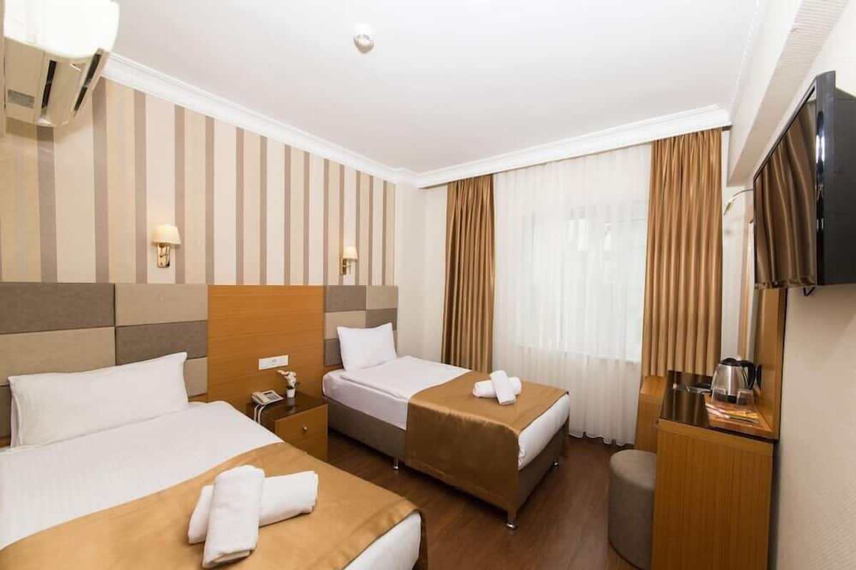 Une chambre d’hôtel avec deux lits, une télévision, un bureau et un petit coin salon.