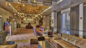 A spacious lobby with a patterned carpet, multiple seating areas including sofas and chairs, and a large chandelier. - Isle of Capri Casino Hotel Boonville & Casino - A Caesars Rewards Destination (Boonville)