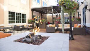 An outdoor patio with a fire feature, seating, and hanging flower baskets. - Isle of Capri Casino Hotel Boonville & Casino - A Caesars Rewards Destination (Boonville)