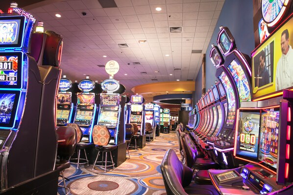 Un casino con numerosas máquinas tragamonedas y un letrero que indica que no se permite fumar.