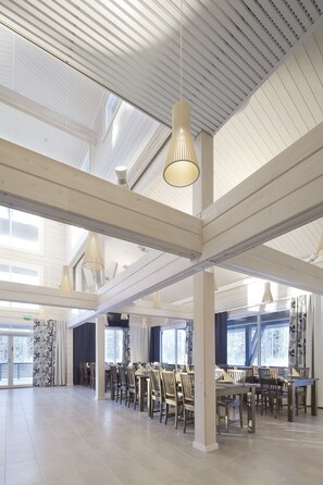 A spacious dining area with high ceilings, large windows, and modern pendant lighting.