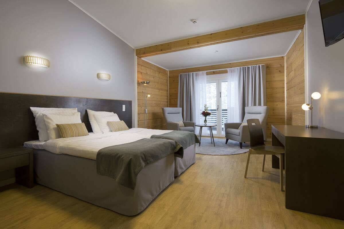 Et moderne hotelværelse med en stor seng, et skrivebord, to stole og et lille bord.