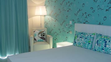 A hotel room with a bed, a chair, a nightstand, and a wall with a pattern.