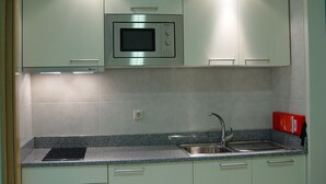 Una cocina con microondas integrado, un lavamanos y encimeras de granito.