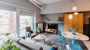 Un salon moderne comprenant un canapé, des fauteuils, une table basse, un téléviseur et un coin repas avec une table et des chaises.