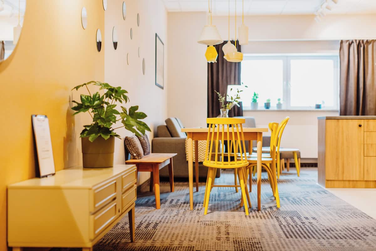 A modern living room with a dining area, featuring a sofa, chairs, a table, and a potted plant.