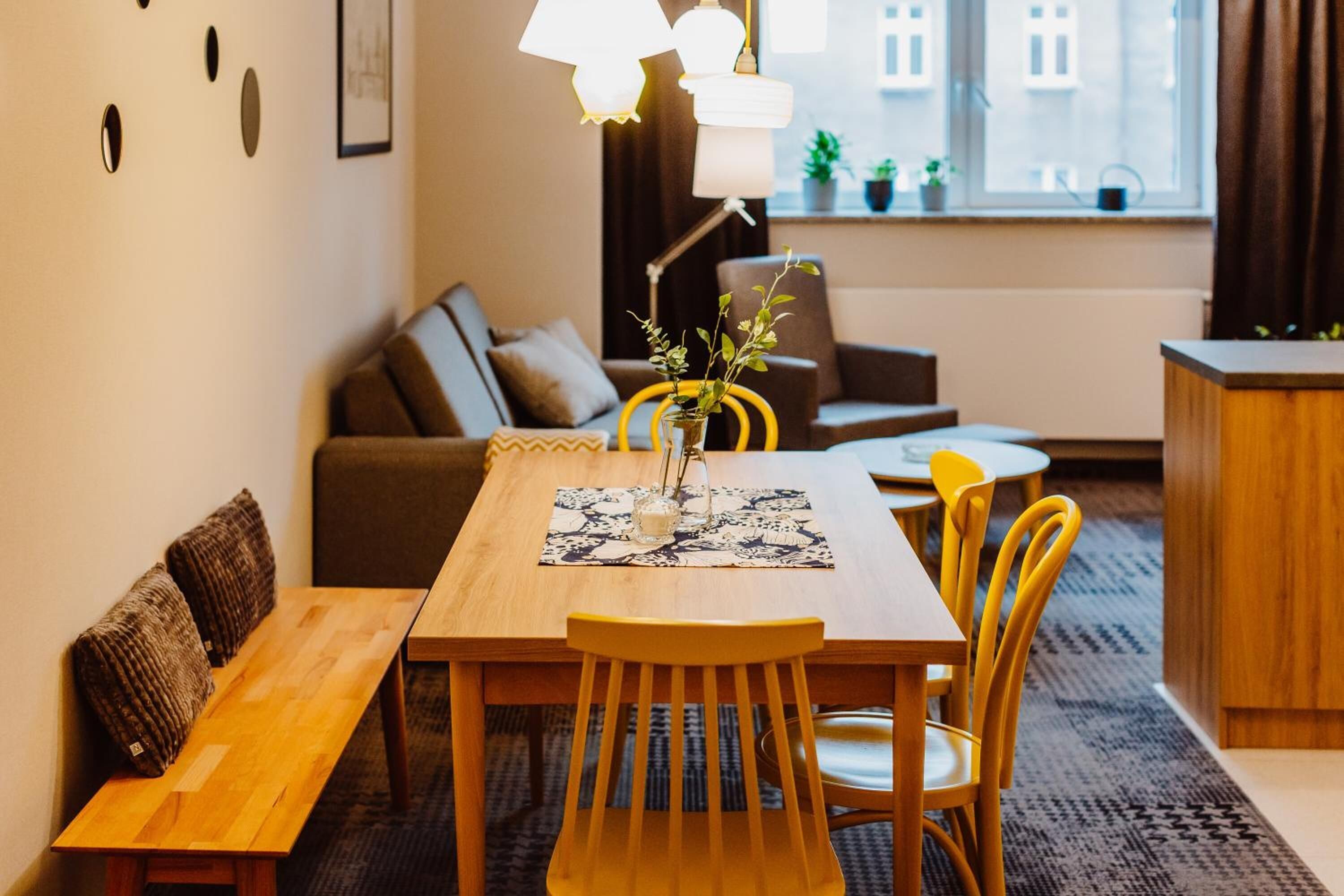 A cozy living room with a wooden dining table, yellow chairs, a sofa, and a coffee table.