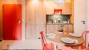 Une cuisine moderne avec des meubles en bois, une porte rouge et un coin repas comprenant une table ronde et des chaises.